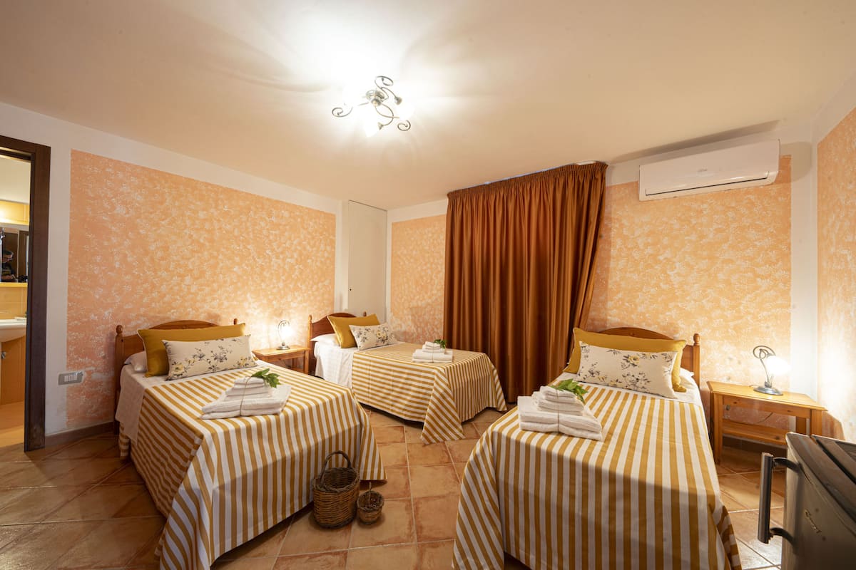 Habitación de hotel con dos camas, cada una con ropa de cama a rayas, cabeceros de madera y mesitas de noche con lámparas.