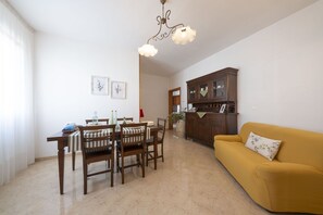 Ein Essbereich mit Tisch und Stühlen, einer Couch, einem Schrank und einer Pendelleuchte.