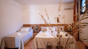 Une chambre avec deux lits, une table de chevet, une commode et une fenêtre avec des rideaux.