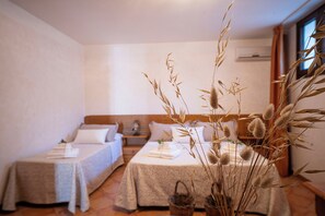 Une chambre avec deux lits, une table de chevet, une commode et une fenêtre avec des rideaux.