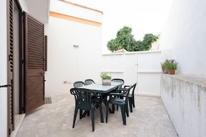 A patio with a table and chairs, a potted plant, and a white wall. - Sentiero del Ciolo (Gagliano del Capo)