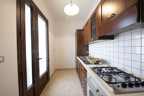 Una cocina con gabinetes de madera, una estufa a gas y salpicadero de azulejos.