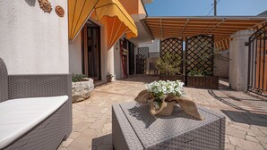 Un patio con mobiliario de mimbre, una planta en maceta y un paraguas amarillo.