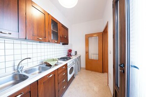Una cocina con gabinetes de madera, un fregadero, una estufa y un microondas.