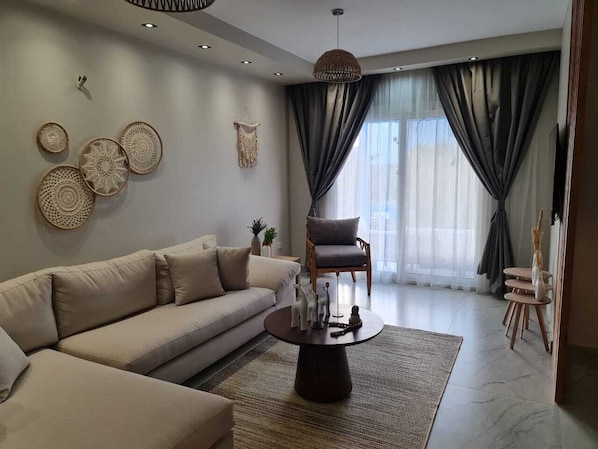A modern living room with a sofa, armchair, coffee table, and decorative wall art.