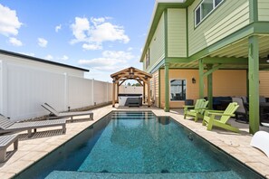 Une piscine avec des chaises longues et un espace barbecue.
