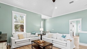 A living room with two white sofas, a wooden coffee table, and a window with blinds. - Seaside Escape  Walk to Beach  Private Pool + Hot Tub (Panama City Beach)