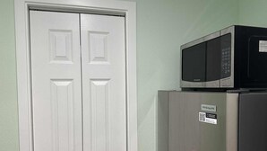 Eine Küche mit einer weißen Doppeltür, einem Edelstahlkühlschrank und einer schwarzen Mikrowelle darüber.