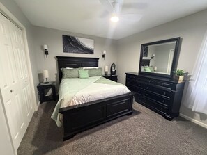 A bedroom with a bed, dresser, mirror, wall art, bedside lamps, and a ceiling fan. - Minutes from KY Lake & close to town! Updated, clean, comfy, huge driveway! (Benton)