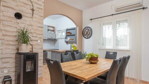 A dining area with a wooden table and black chairs, a potted plant, and a kitchen in the background. - Villa Josefina – Heated Pool Holiday Home near Split, Trilj (Košute)