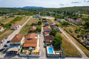 An aerial view of a residential area with houses, a swimming pool, and a large building with a red roof.