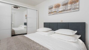 A modern bedroom with a bed, a grey headboard, and a large mirror. - Villa Josefina – Heated Pool Holiday Home near Split, Trilj (Košute)