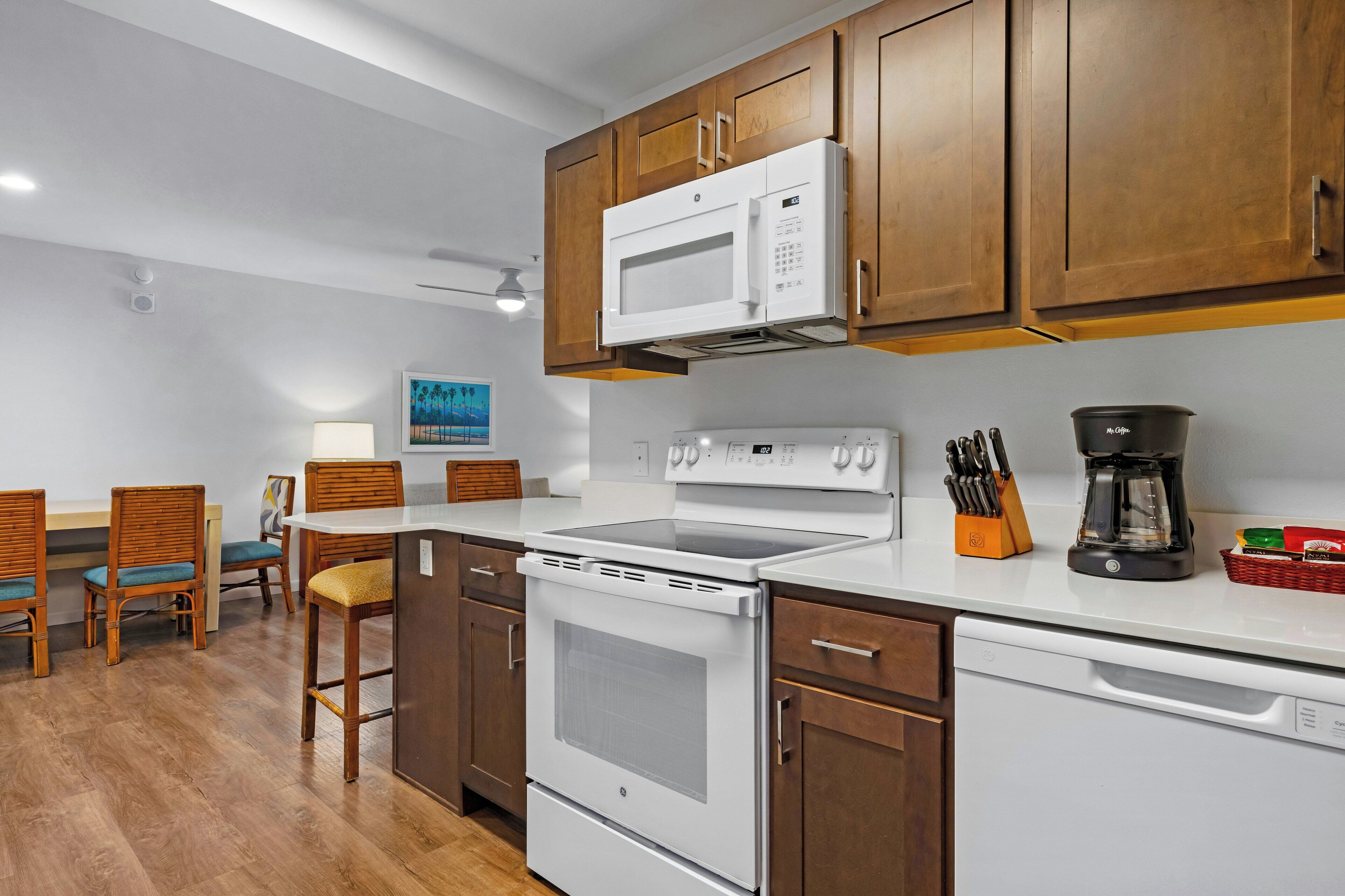 A kitchen with wooden cabinets, a microwave, a stove, and a coffee maker.