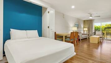 A hotel room with a bed, a desk, a chair, a sofa, and a balcony with a view.