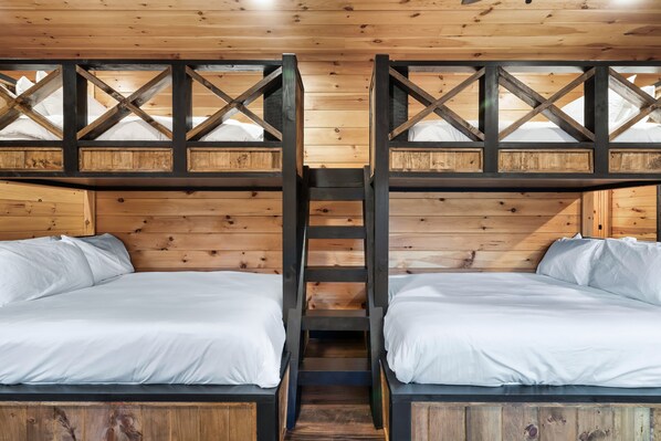 A bunk bed room with wooden walls and a ladder connecting the beds.
