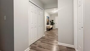 A hallway with white doors, a wooden floor, and a painting on the wall.