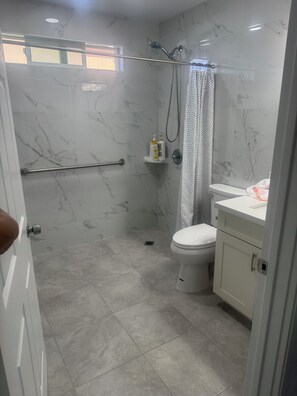 A bathroom with a shower, toilet, and marble walls.