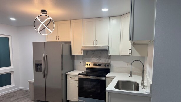 A modern kitchen with white cabinets, stainless steel appliances, and a marble backsplash. - Kalihi Stream, Coffee Bar, Ro Water, Split Ac, WIFI, Black Out Curtain, 4Parking (Honolulu)