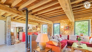 A spacious living area with a wooden ceiling, a stone wall, and a red sofa. - Gîte des Châtelaines - ANZY LE DUC (ANZY LE DUC)