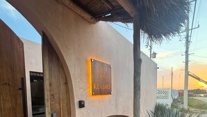 Un edificio con puerta de madera, una gran maceta de barro y un letrero que dice "KENSHO".