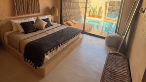 Un dormitorio con una cama grande, ventilador de techo y vista a una piscina a través de una puerta corrediza de vidrio.