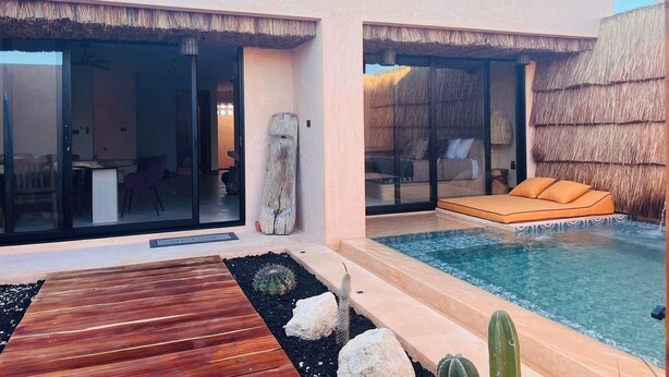 Un resort moderno con piscina, terraza de madera y habitaciones con techo de paja.