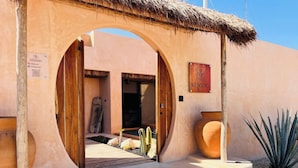 Una entrada de edificio con un arco de madera, un letrero que dice "KENSHO" y una estructura de techo de paja.