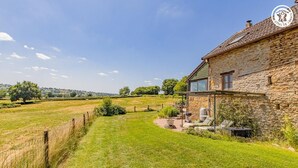 A stone house with a garden and a view of the countryside. - Gîte du Bois de la Velle (VIRY)