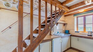 A kitchen with wooden beams, a window with a view, and a sink. - Gîte du Bois de la Velle (VIRY)