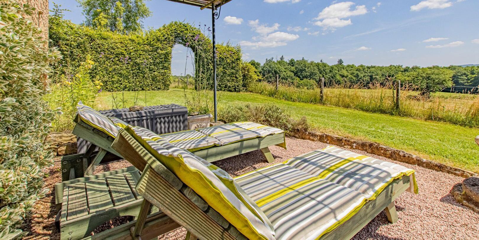 Un jardín con un banco de madera y una pérgola.