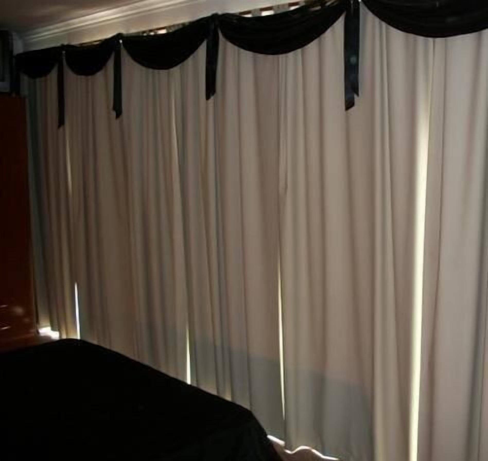 Una habitación con un ventanal cubierto por cortinas blancas y translúcidas, y un paño de ventana oscuro.