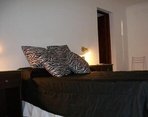 Una camera da letto con un letto, un comodino, una lampada e una sedia.