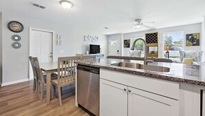 Una cocina moderna con armarios blancos, lavavajillas de acero inoxidable y encimera de granito.