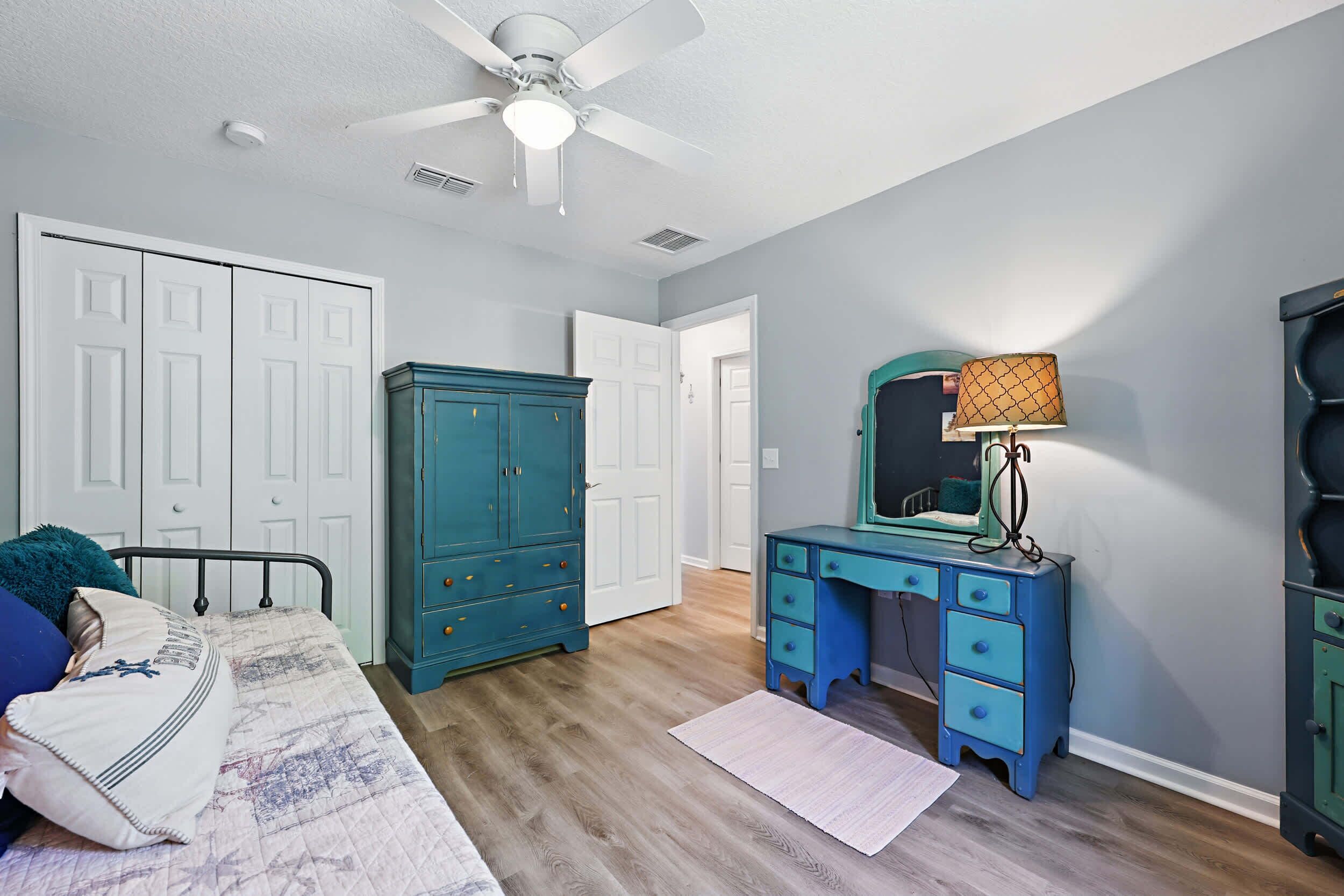 Une chambre à coucher comprenant un lit, une commode, un bureau et un ventilateur de plafond.