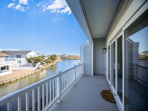 A balcony with a view of a river and houses, a white railing, and a small rug.