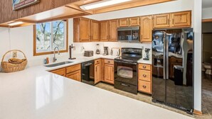 A kitchen with wooden cabinets, a microwave, a refrigerator, and a sink. - Spacious 5-Bedroom Home Near Beach (Bethany Beach)