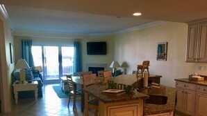 A spacious living area with a kitchen island, a dining table, and a sofa. - Beachfront 3-Bedroom Condo near Shops (Bethany Beach)