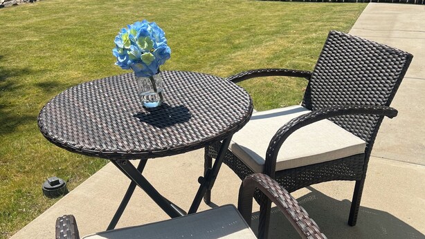 A patio with a round table and two wicker chairs, a small vase with flowers, and a wooden fence in the background. - Charming 3-bedroom house with AC, WiFi in fantastic Susanville (Susanville)