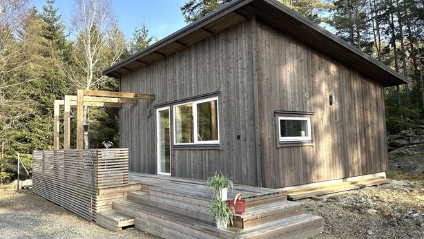 Een houten hut met een veranda, een klein raam en een deur.