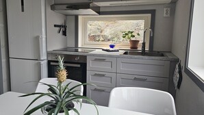 Een kleine keuken met een raam, een spoelbak en een koelkast.