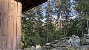 Een houten chalet met uitzicht op een bos en rotsachtig terrein.