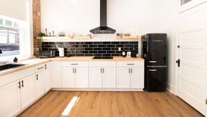 A modern kitchen with white cabinets, a black refrigerator, and a black backsplash. - Modern Loft in Lively SoMa Downtown (Little Rock)