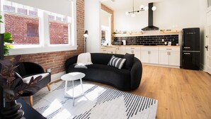 A modern living room with a black sofa, a white coffee table, and a patterned rug. - Modern Loft in Lively SoMa Downtown (Little Rock)