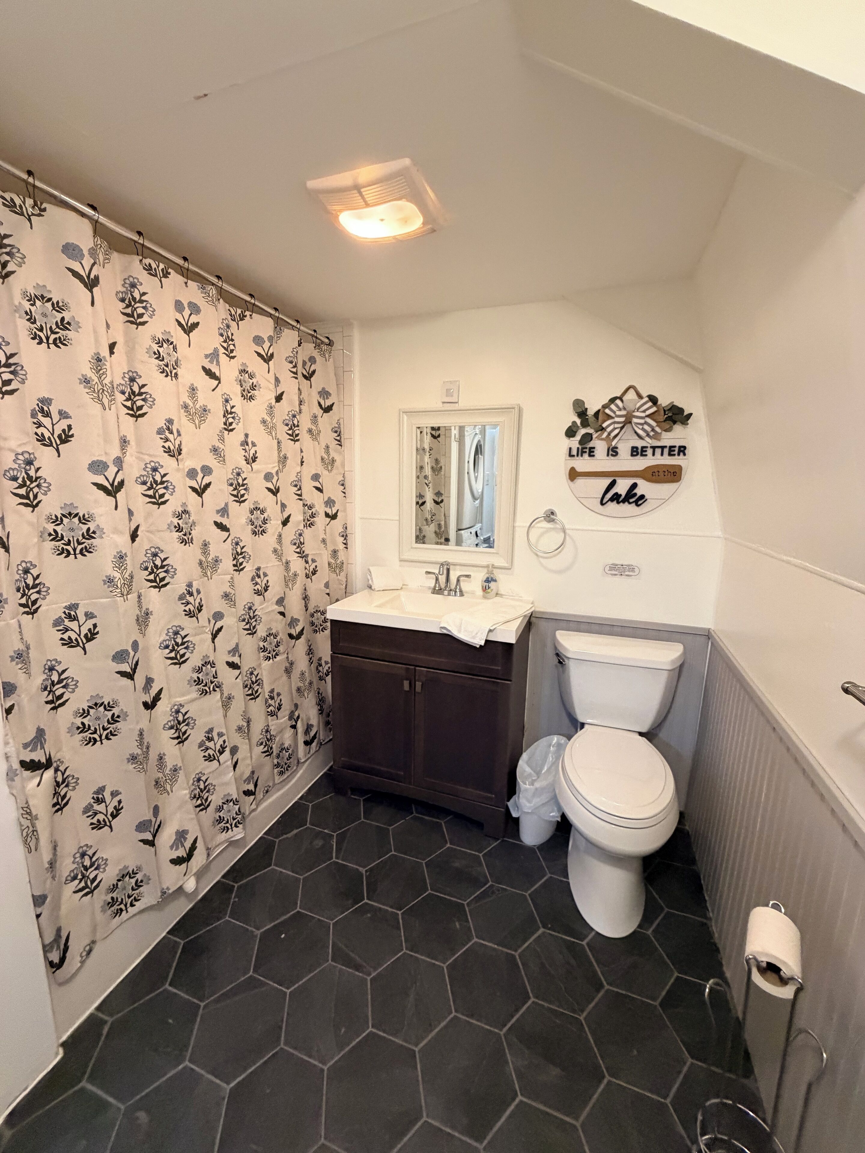 Baño con inodoro, lavamanos y cortina de ducha.