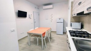 A compact kitchen with a dining table, chairs, a refrigerator, a microwave, and a stove.