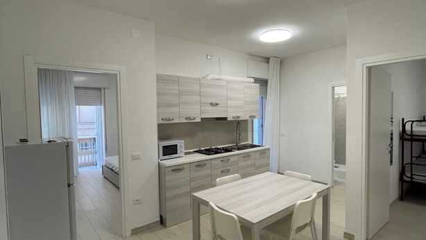 A compact kitchen with a dining area, a refrigerator, and a microwave.