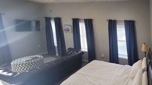 A bedroom with a bed, a sofa, and curtains. - Remodeled downtown studio with remarkable views! (Luverne)