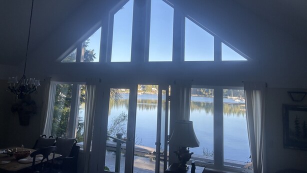 A room with a large skylight, a dining area with chairs and a table, and a view of a lake. - Stunning Waterfront Retreat In Port Madison, Bainbridge Island-Furnished (Bainbridge Island)
