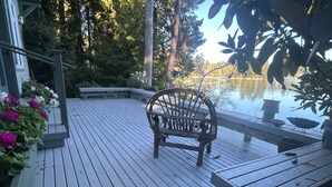 A wooden deck with a bench and a table, overlooking a calm lake. - Stunning Waterfront Retreat In Port Madison, Bainbridge Island-Furnished (Bainbridge Island)