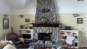 A cozy living room with a stone fireplace, comfortable seating, and decorative items. - Stunning Waterfront Retreat In Port Madison, Bainbridge Island-Furnished (Bainbridge Island)